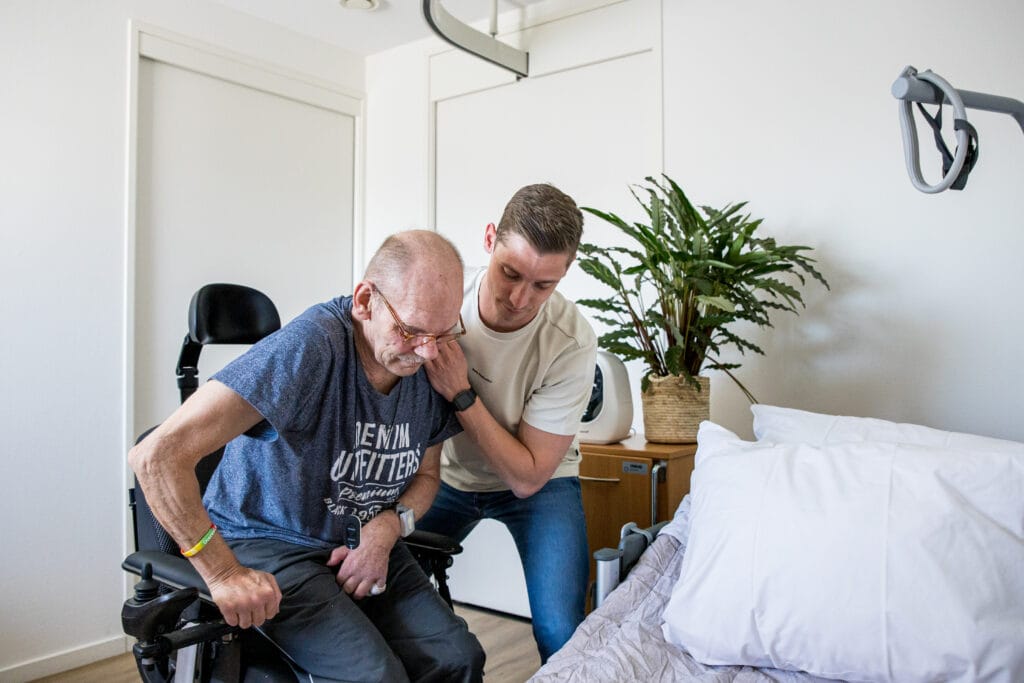 Cliënt oefent samen met fysiotherapeut met opstaan uit de rolstoel